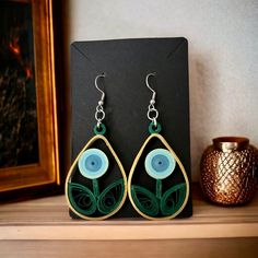 a pair of earrings sitting on top of a wooden table next to a vase with flowers