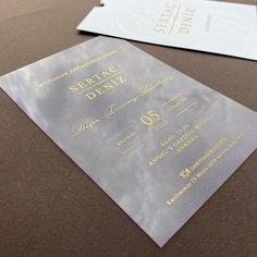 two silver and gold wedding cards sitting on top of a table