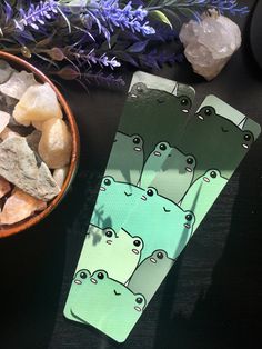 two green bookmarks sitting on top of a table next to a bowl of rocks