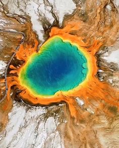 an aerial view of a lake surrounded by mountains in the middle of snow covered ground