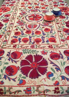 a table covered with red, blue and green floral designs on top of a white table cloth