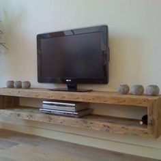 a flat screen tv sitting on top of a wooden shelf next to a potted plant