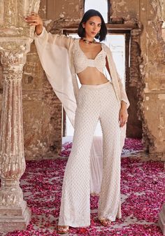 Elevate your elegance with the Ivory Cape set. This luxurious ensemble features a georgette blouse adorned with pearls, beads, crystals, sequins, and resham threads. Paired with embroidered habutai silk pants and a luxurious organza cape. An knockout indo western pick for family gathering and casual outings. Composition : Blouse - Georgette, Pant - Habutai silk, Cape - Organza, Satin lining Care: Dry Clean Only and Vacuum Storage This product can be customized for sleeves, length and colour Delivery : 4-6 weeks as the product is hand crafted. Check Size Guide or choose MySize for free customisation (All Sizes above XL can be made at 15% additional cost) For more information and sizes please contact fabiliciousfashion@gmail.com or visit our Copenhagen studio. About the Designer : Seema Thuk Seema Thukral, Organza Cape, Ivory Pants, Cape Set, Silk Cape, Ivory Blouse, London College Of Fashion, Ready To Wear Saree, Indian Wedding Wear