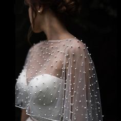 the back of a woman's wedding dress with pearls on it