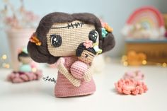 a knitted doll holding a baby doll next to other crocheted dolls and flowers