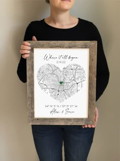 a woman is holding up a framed map