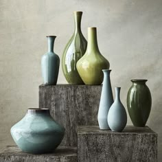 there are many different vases sitting on the wooden block in front of each other