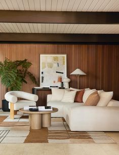 a living room with wood paneling and white furniture