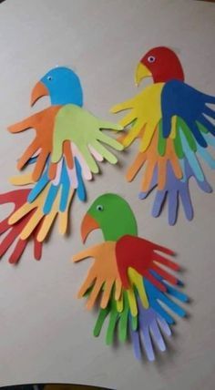 three colorful birds made out of paper on a table