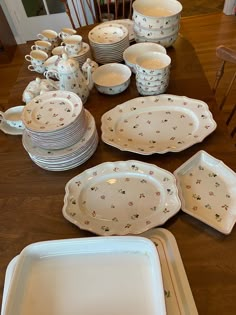 a table topped with lots of white dishes and plates on top of a wooden table