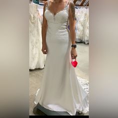 a woman in a white wedding dress is holding a red heart and looking at the camera