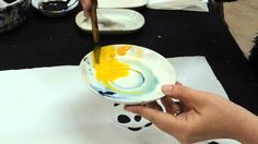 a person is painting on a plate with yellow paint