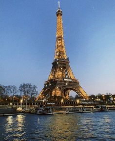 the eiffel tower lit up at night with lights reflecting off it's water