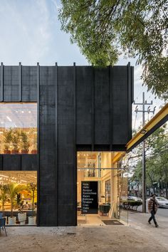 a black building with lots of windows and people walking by