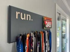 a row of medals hanging on a wall next to a sign that reads, run