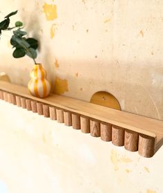 a wooden shelf with two vases on it and a plant in the corner next to it