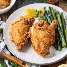 fried chicken and asparagus on a plate with lemon wedges next to it