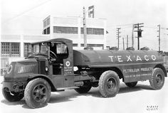 an old black and white photo of a texaco truck in front of a building