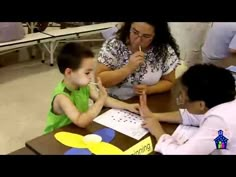 a woman sitting at a table with a child in front of her and an adult