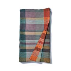 a multicolored plaid blanket folded on top of a white wall with an orange and green stripe