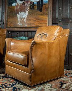 two brown leather chairs sitting in front of a painting