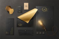 an assortment of stationery items with gold foil on black paper, including a light bulb and business cards