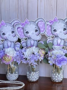 three vases filled with purple and white flowers sitting on a table next to pearls