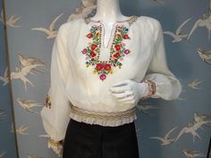 Stunning vintage hand embroidered peasant blouse dating from 1970s. Made from a semi-sheer Diolen polyester fabric, it has a beautiful embroidered floral design in primary colours on the front and sleeves. It has wide puff sleeves, smocking at the neckline, waist and cuffs, and blanket stitched rolled hems. It fastens at the side with silver poppers. Labelled size 38, would fit a UK 8/ 10. Measures a loose fitting 40" bust. Waist 24" stretching to 28". Length 18.5" from shoulder to hem. In excel Traditional Spring Blouse With Machine Embroidery, Traditional Spring Peasant Top With Embroidered Neckline, Spring Folk Peasant Top With Embroidered Border, Spring Peasant Top With Embroidered Border, Spring Embroidered Border Peasant Top, Spring Embroidered Peasant Top, Spring Peasant Blouse With Embroidered Border, Fitted Traditional Embroidered Peasant Top, Traditional Spring Peasant Top With Embroidered Border