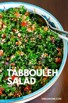 a bowl full of tabbouleh salad on top of a wooden table with a spoon in it