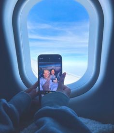 a person taking a photo of themselves in an airplane window with their cell phone,