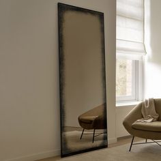 a large mirror sitting next to a couch in a living room