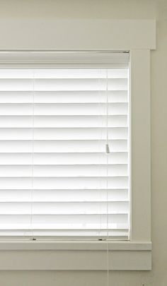 a window with white blinds in the corner and an electrical cord hanging from it's side