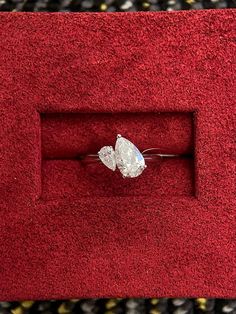 a diamond ring sitting on top of a red velvet box in a carpeted area