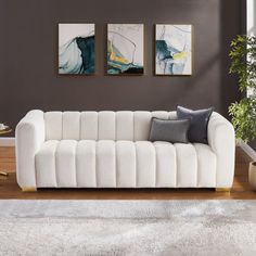 a living room with two paintings on the wall and a white couch in front of it