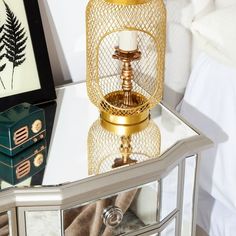 a gold candle holder sitting on top of a mirrored table next to a mirror box