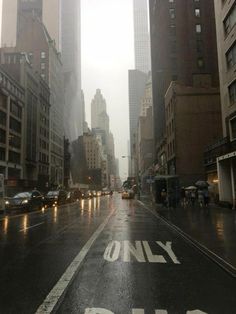 an empty city street in the rain with tall buildings