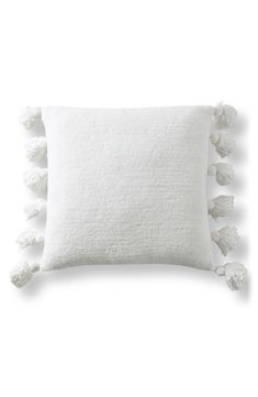 a white pillow with pom poms on the front and back of it,