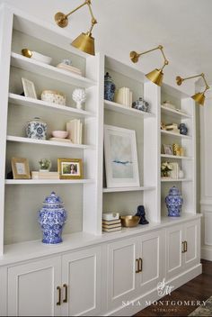 a white bookcase with blue and white vases on the front, and gold accents on the back