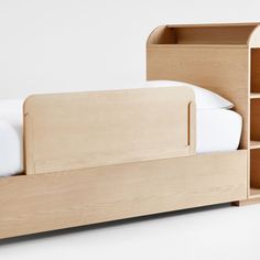 a bed with a wooden headboard and bookcase next to it on a white surface