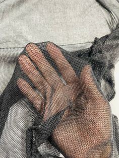 a person's hand holding onto a piece of mesh on top of a shirt