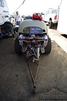 an engine is attached to the back of a vehicle with two people standing around it