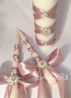 wedding candles with pink ribbons and pearls on the top one candle has a white pillar in the middle