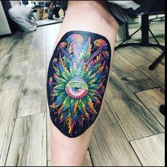 a person with a colorful tattoo on their arm and leg, holding an eyeball