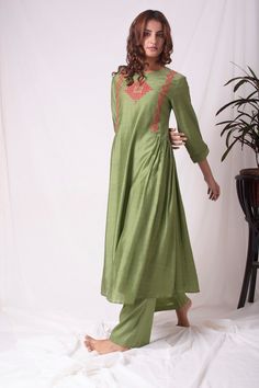 Beautiful green cotton silk suit is a stunning choice for weddings and festive occasions! The suit is crafted with fine simple red design work. Kurta has 3/4 length sleeves. Kurta has pleating on one side. It has a complementing green color palazzo. The suits simplicity gives it a unique and lovely look. Buy online from Pure Elegance. Disclaimer: The actual product may vary slightly from the image. These are custom orders, hence expect slight variation in color, placement of the motif or buta. E Green Slub Silk Designer Dress, Green Slub Silk Straight Kurta Dress, Green Slub Silk Dress With Traditional Drape, Green Cotton Silk Palazzo Set For Diwali, Designer Green Embroidered Pant Set, Designer Embroidered Green Pant Set, Diwali Green Cotton Silk Palazzo Set, Green Anarkali Cotton Silk Palazzo Set, Festive Green Slub Silk Kurta