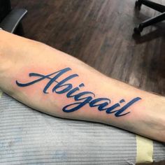 a person with a tattoo on their arm that says, alogail in cursive writing