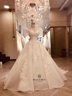 a white wedding dress on display in a store with chandelier hanging from the ceiling