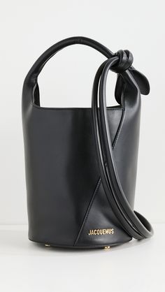 Find JACQUEMUS Le Petit Tourni on Editorialist. Cowhide. Gold-tone logo emblem and hardware. Structured base. Knotted shoulder strap. Patch and zip interior pockets. Magnetic snap. Suede lining. Weight: 20oz / 0.57kg. Made in Italy. Measurements: Height: 9.5in / 24cm Length: 7.75in / 19.5cm Depth: 7.75in / 19.5cm Strap drop: 10.75in / 27cm Handle drop: 5in / 12.5cm Neon Bag, Black Cow, Logo Emblem, Leather Bucket Bag, Leather Bucket, Metallic Logo, Emblem Logo, Blue Bags, Cow Leather