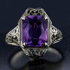 Description: Step back in time with this exquisite 14K white gold Art Deco ring, featuring a stunning emerald-cut purple amethyst. Weighing 2.2 grams, this ring showcases intricate filigree details that epitomize the elegance of the Art Deco era. The vibrant purple amethyst is perfectly framed by the ornate design, making this ring a true statement piece for any vintage jewelry lover. Specifications: Metal: 14K White Gold Weight: 2.2 grams Main Stone: Amethyst Main Stone Shape: Emerald Main Ston Elegant Rectangular Amethyst Ring For Formal Occasions, Classic Octagon Amethyst Ring As Gift, Classic Octagon Amethyst Ring As A Gift, Classic Octagon Amethyst Ring For Gift, Art Deco Oval Purple Amethyst Ring, Classic Amethyst Ring With Rectangular Stone For Formal Occasions, Classic Emerald Cut Purple Rings, Classic Purple Emerald Cut Rings, Luxury Purple Amethyst Ring, Rectangular Shape