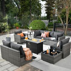 an outdoor living room with grey wicker furniture and orange throw pillows on the floor