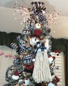 a christmas tree decorated with plaid ornaments and black and white ribbon, snowman ornament